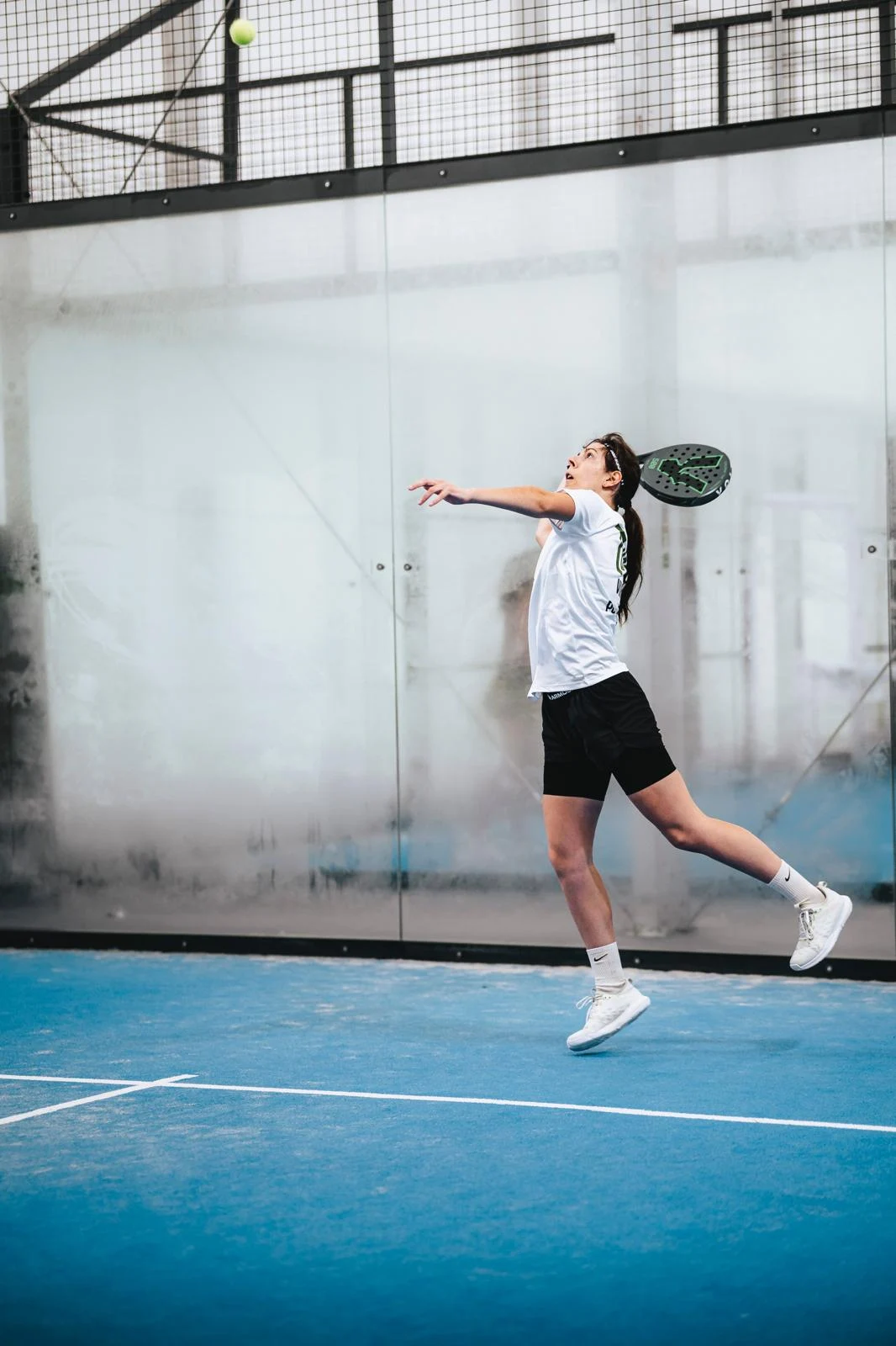 Flávia Macedo executa um golpe acima da cabeça num campo de padel